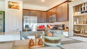 Una cocina moderna con armarios de madera, electrodomésticos de acero inoxidable y un comedor con una mesa lista para cuatro comensales.