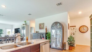 Una cocina moderna con lavavajillas, un lavabo y una zona de comedor con sillas de madera.