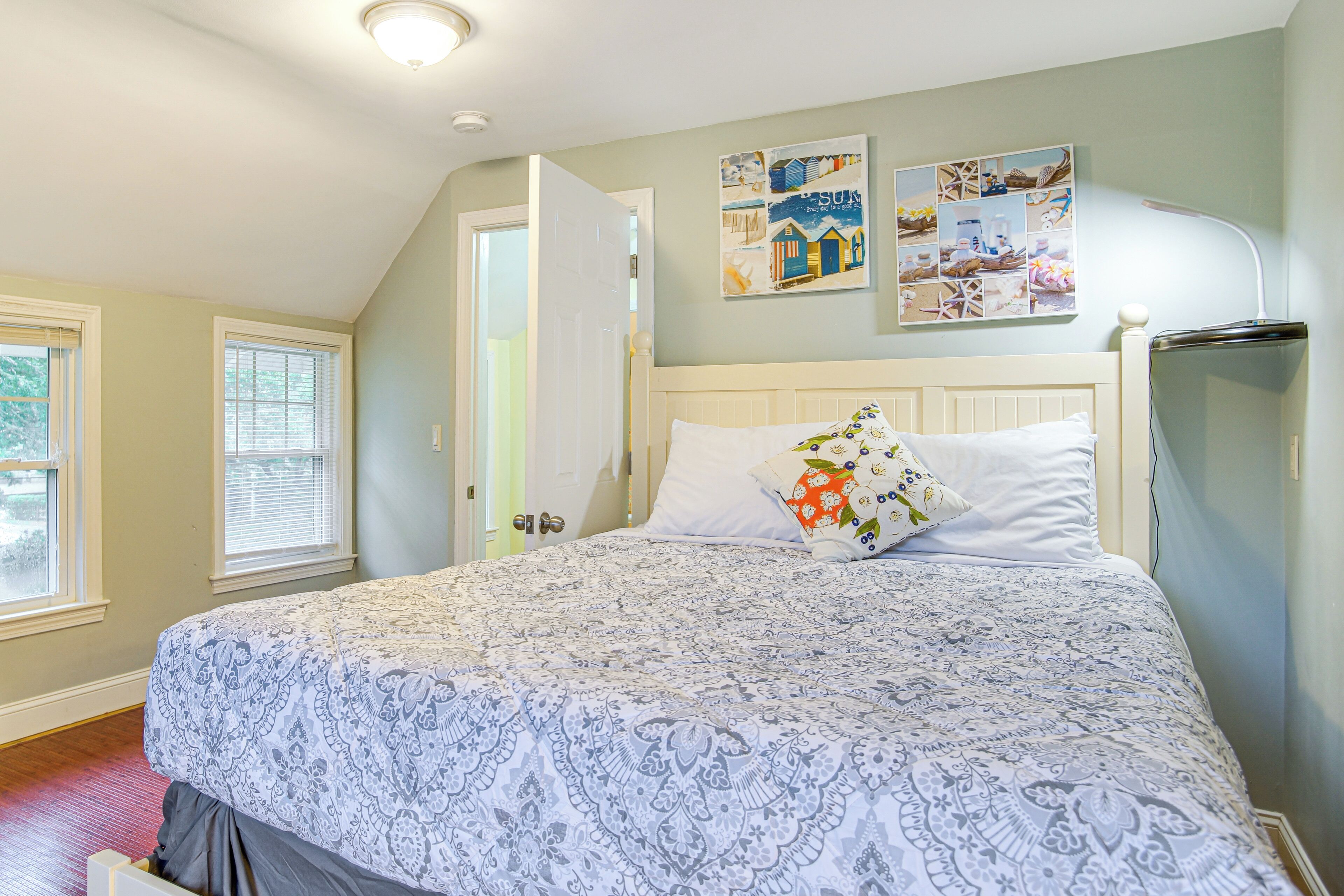 A bedroom with a large bed, a white headboard, and a wall-mounted artwork.