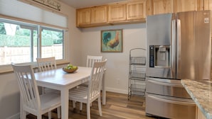 A kitchen with white cabinetry, a stainless steel refrigerator, a dining table with chairs, and a window with blinds. - 6 Mi to Denver: Wfh-friendly Duplex in Wheat Ridge (Wheat Ridge)