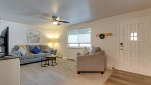 A living room with a grey sofa, a grey armchair, a small table, a TV, a ceiling fan, a window, and a door. - 6 Mi to Denver: Wfh-friendly Duplex in Wheat Ridge (Wheat Ridge)