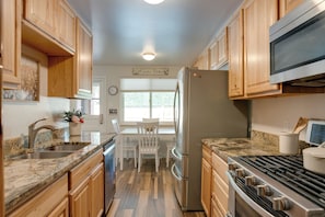 A kitchen with wooden cabinets, a stainless steel refrigerator, a stove, and a window with a view of the outdoors. - 6 Mi to Denver: Wfh-friendly Duplex in Wheat Ridge (Wheat Ridge)