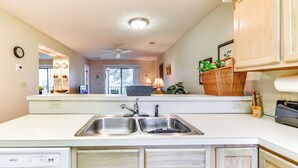 A kitchen with a double sink, a dishwasher, wooden cabinets, a ceiling fan, and a window with a view of the outside. - Little River Condo w/ Pool Access: 5 Mi to Beach (Little River)