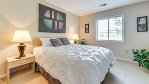 A bedroom with a large bed, two bedside tables with lamps, a window with blinds, and a wall art piece. - Little River Condo w/ Pool Access: 5 Mi to Beach (Little River)