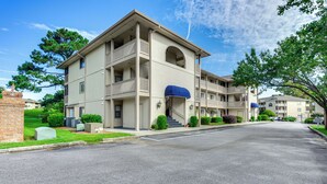 A multi-story building with a central entrance, balconies, and a covered area with a blue awning. - Little River Condo w/ Pool Access: 5 Mi to Beach (Little River)