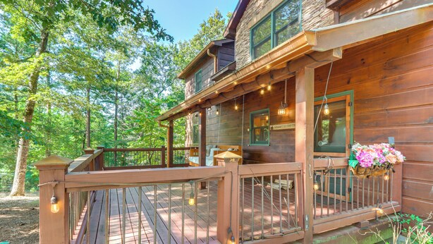 A wooden cabin with a deck, string lights, and a flower basket. - Deck & Private Hot Tub: Cabin in Ellijay! (Ellijay)
