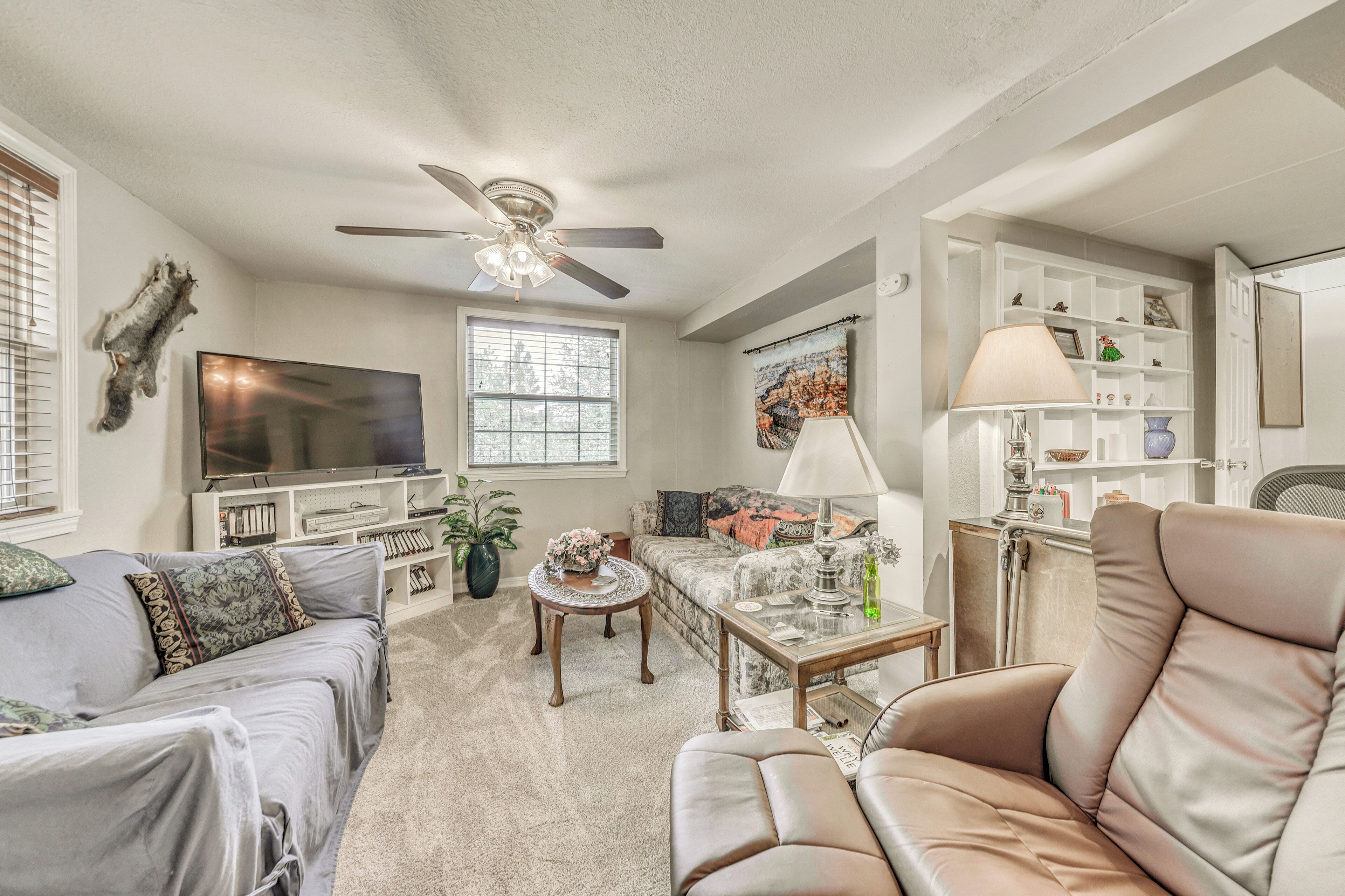 A living room with a ceiling fan, a flat-screen TV, a sofa, a coffee table, and a lamp.