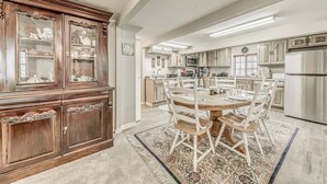 Een ruime keuken met een centraal eiland, houten kasten en een eethoek met een ronde tafel en stoelen.