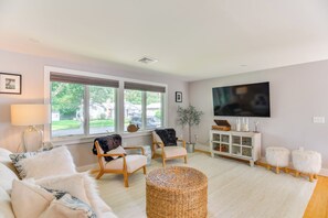 A living room with a sofa, two armchairs, a TV, a lamp, a plant, and a small cabinet. - Coastal-modern Home < 3 Mi to Charlestown Beach! (South Kingstown)