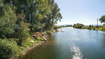 A river with a wooden bridge and lush greenery on the banks.