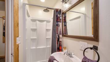 A bathroom with a shower, sink, and mirror.