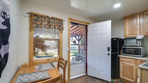 A compact kitchen with a dining table, wooden cabinets, a refrigerator, and a microwave. - 'crater Lake' Williamson River Resort Cabin 1 (Chiloquin)