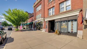 A street view with a brick building, storefronts, and a sidewalk. - Chic Apt in the Heart of Downtown Canandaigua (Canandaigua)