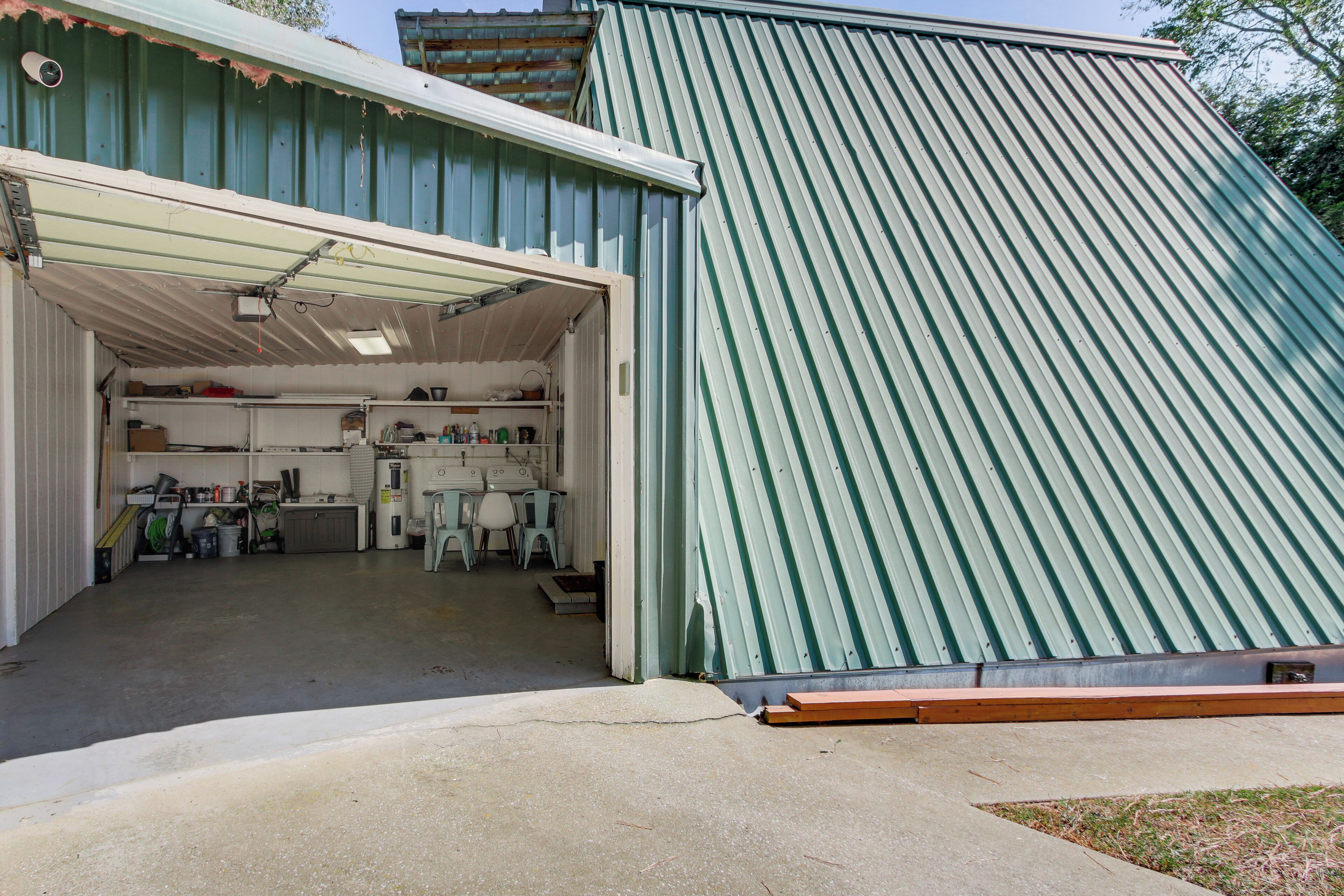Un garage con tetto in lamiera verde ondulata e porta aperta che mostra un’officina con attrezzi e attrezzature.