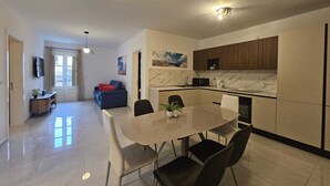 A modern kitchen with a marble countertop, a dining table with chairs, and a built-in oven. - Cozy Modern two Bdr Place Sliema Ferry Tigne Point (Sliema)