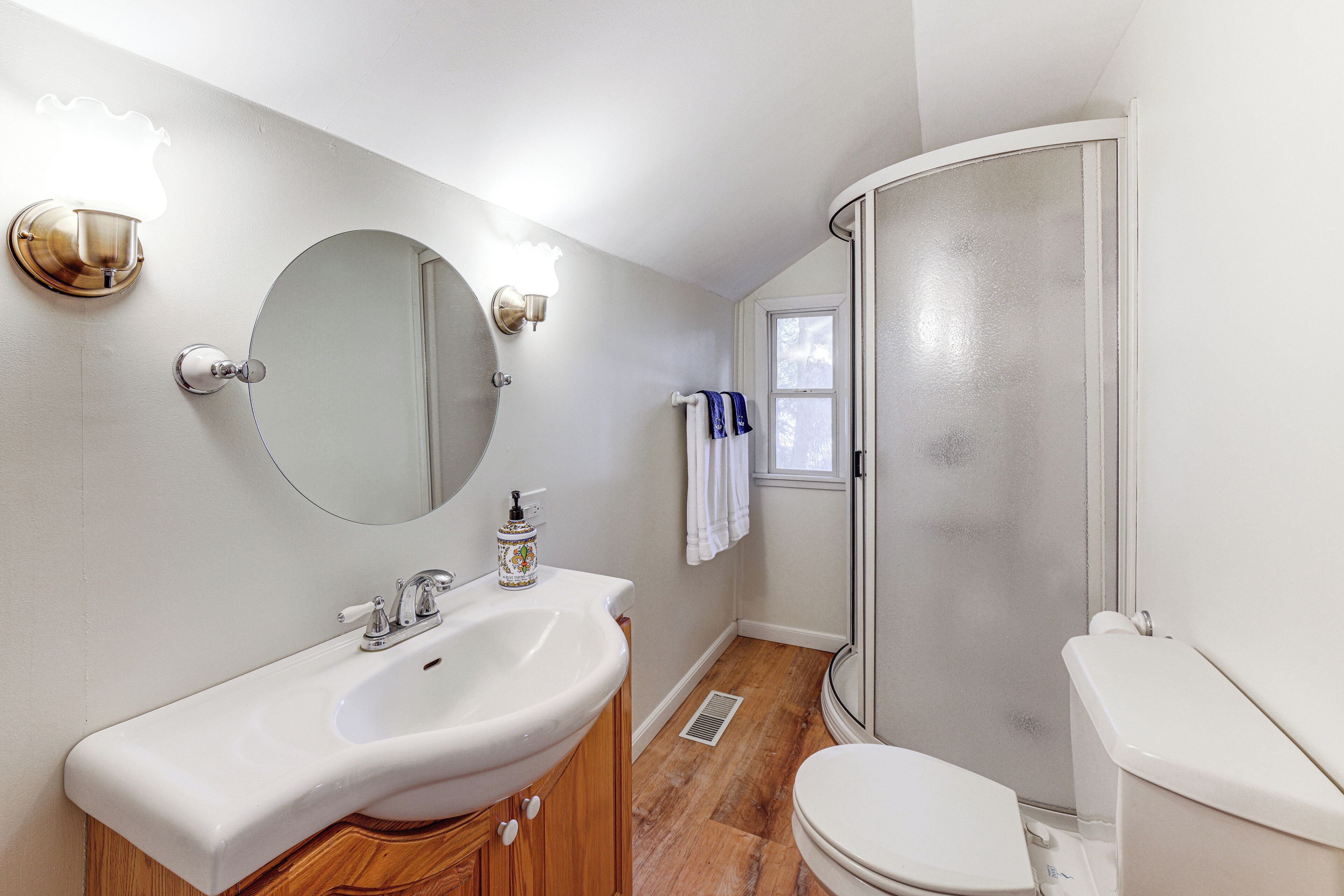 A bathroom with a white sink, mirror, and toilet.