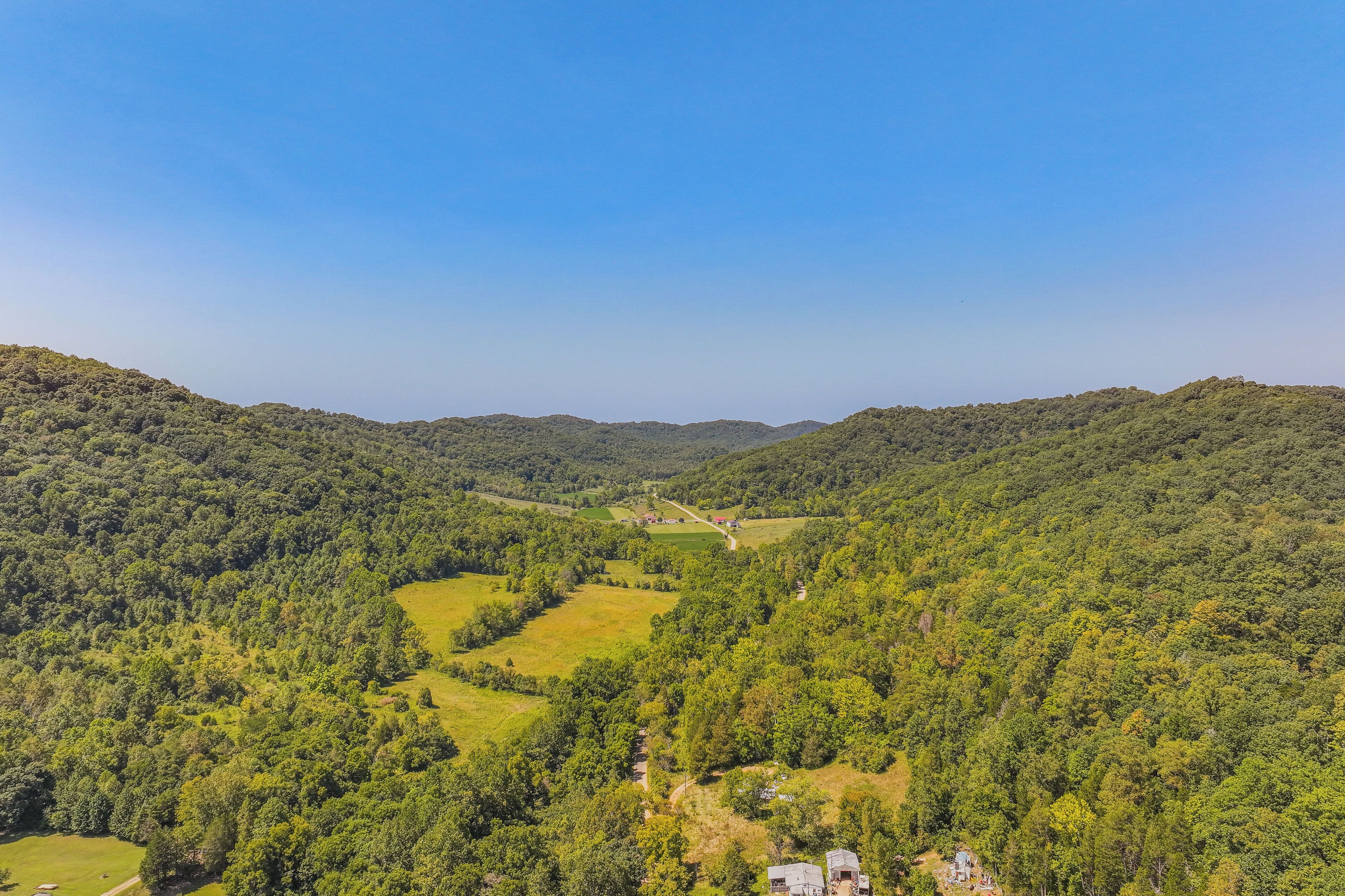 A panoramic view of a lush valley with dense forests and rolling hills.