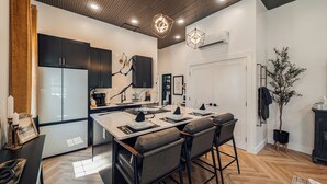 Une cuisine moderne dotée d’un îlot central, de meubles de rangement noirs et d’un parquet en bois disposé en chevrons.
