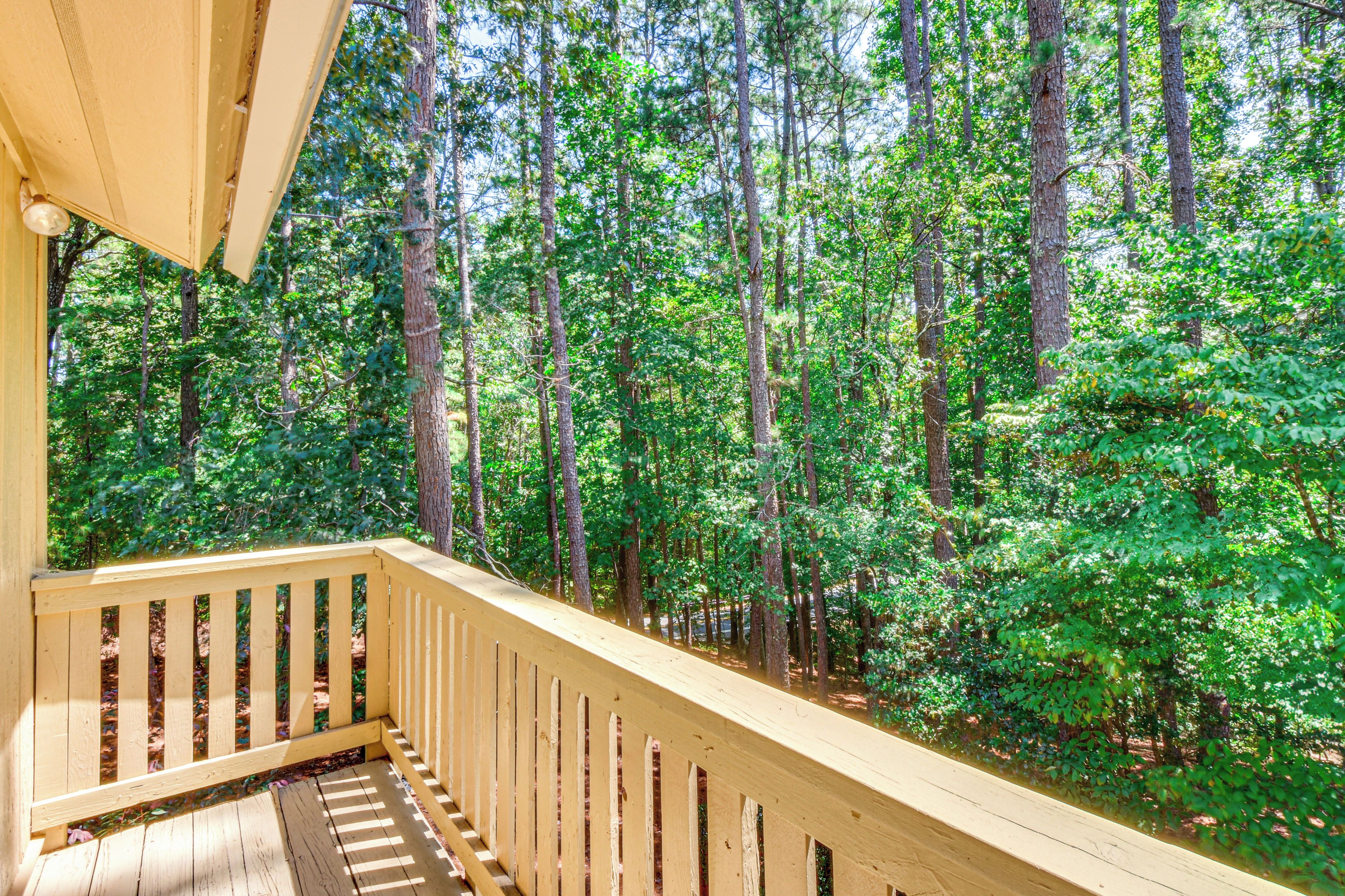 A wooden deck with a railing overlooking a forested area.
