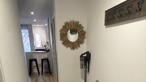 A hallway with a wooden floor, a bench, a mirror, and a wall-mounted light fixture. - Agréable Appartement de Type F3 (Argelès-sur-Mer)