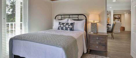 A bedroom with a bed, bedside table, lamp, and a view of the hallway.