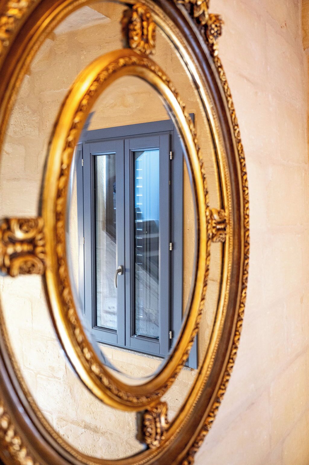 A mirror with an ornate gold frame reflecting a door with a window.