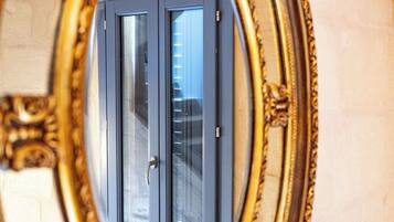 A mirror with an ornate gold frame reflecting a door with a window.