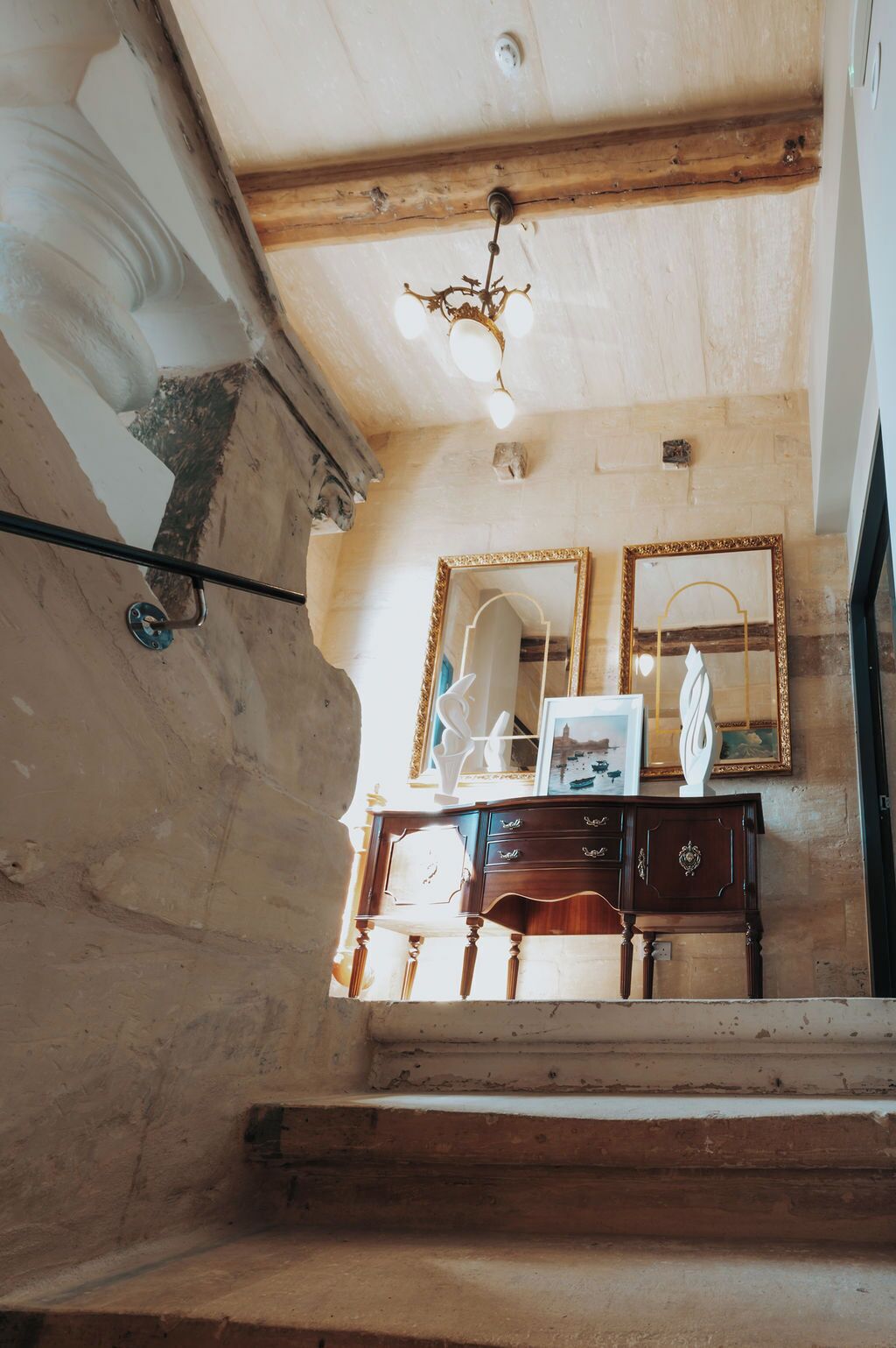 Quarto com teto de madeira, um candelabro, um espelho e um aparador com gavetas.