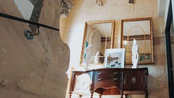Quarto com teto de madeira, um candelabro, um espelho e um aparador com gavetas.