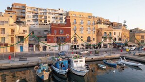 Una marina con barcos amarrados, una calle con edificios y un cielo despejado.