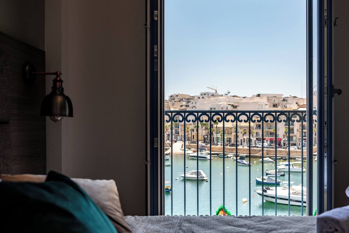 A bedroom with a view of a marina through an open door.
