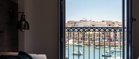 A bedroom with a view of a marina through an open door.