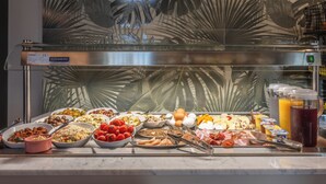 Un bufé con diferentes opciones de comida y un dispensador de zumo.