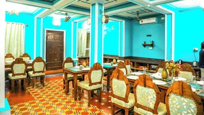 Un comedor con mesas y sillas, un piso estampado y una pared azul.