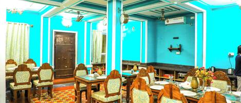 A dining area with tables and chairs, a patterned floor, and a blue wall.