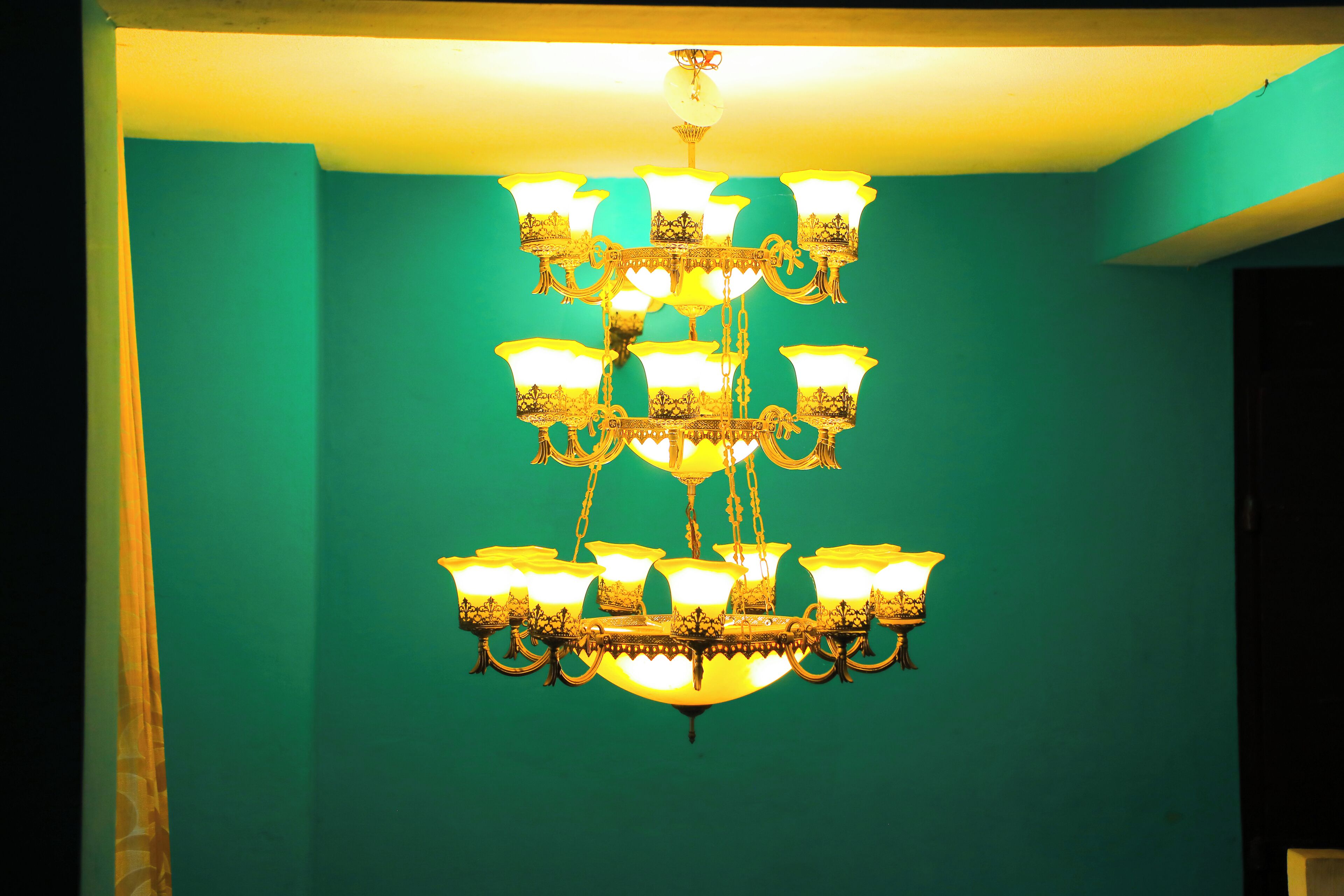 A chandelier with multiple light fixtures against a teal wall.
