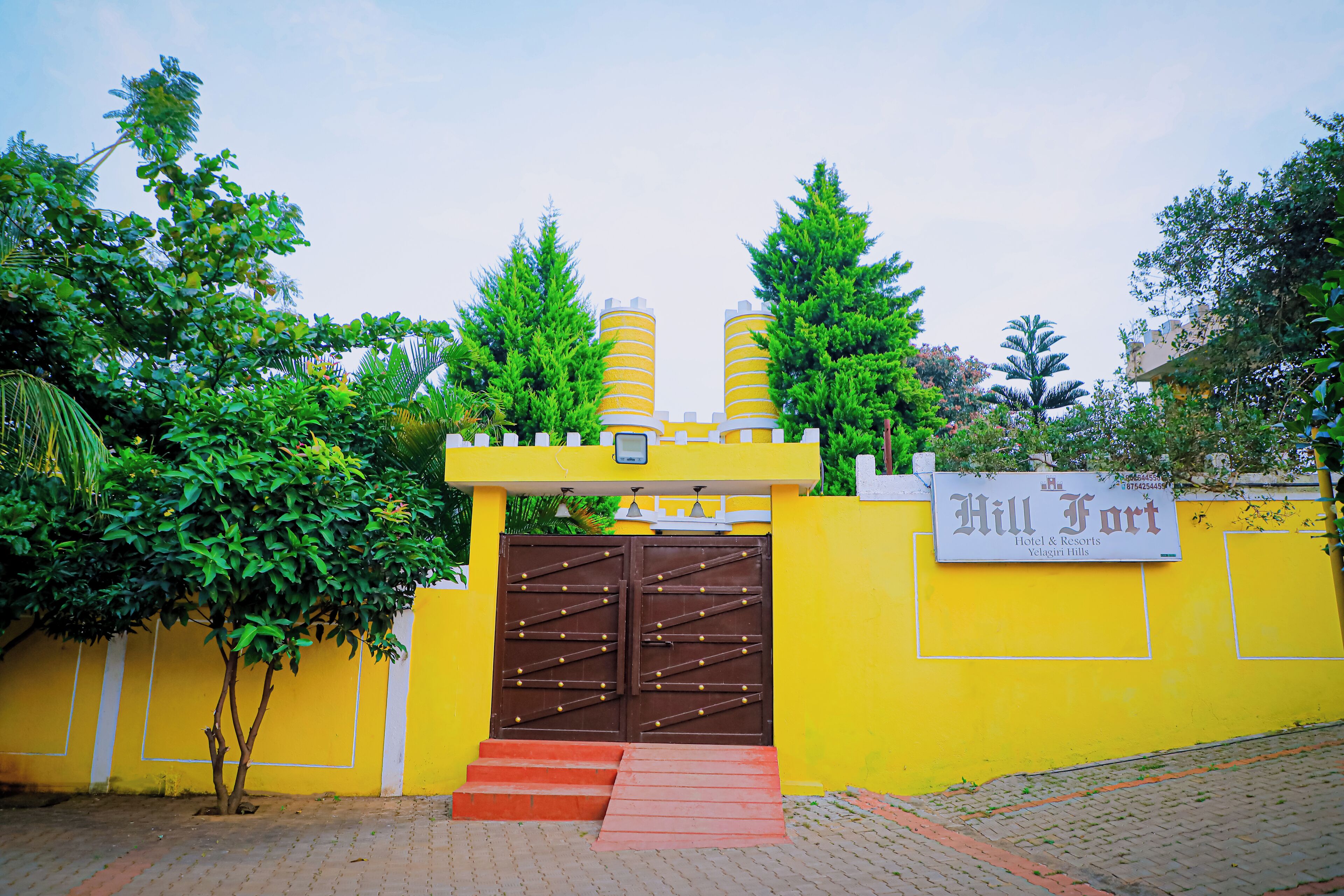 A yellow building with a sign reading "Hill Fort Hotel & Resorts Yelagiri Hills."