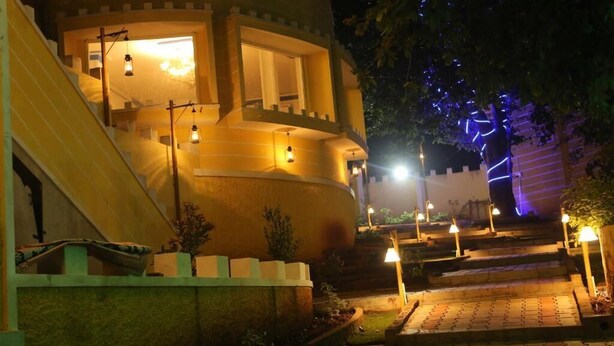 Un edificio con fachada curva, una escalera que conduce a la entrada e iluminación exterior.