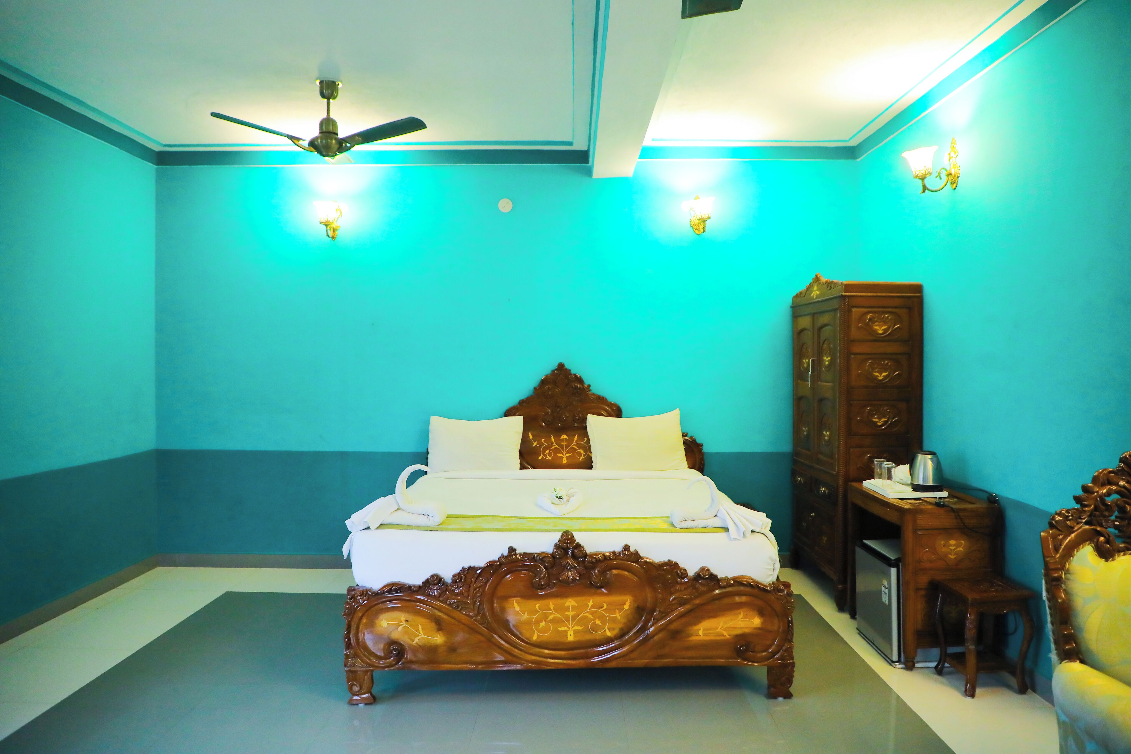 Quarto com cama, escrivaninha, cadeira, guarda-roupa e ventoinha no teto.