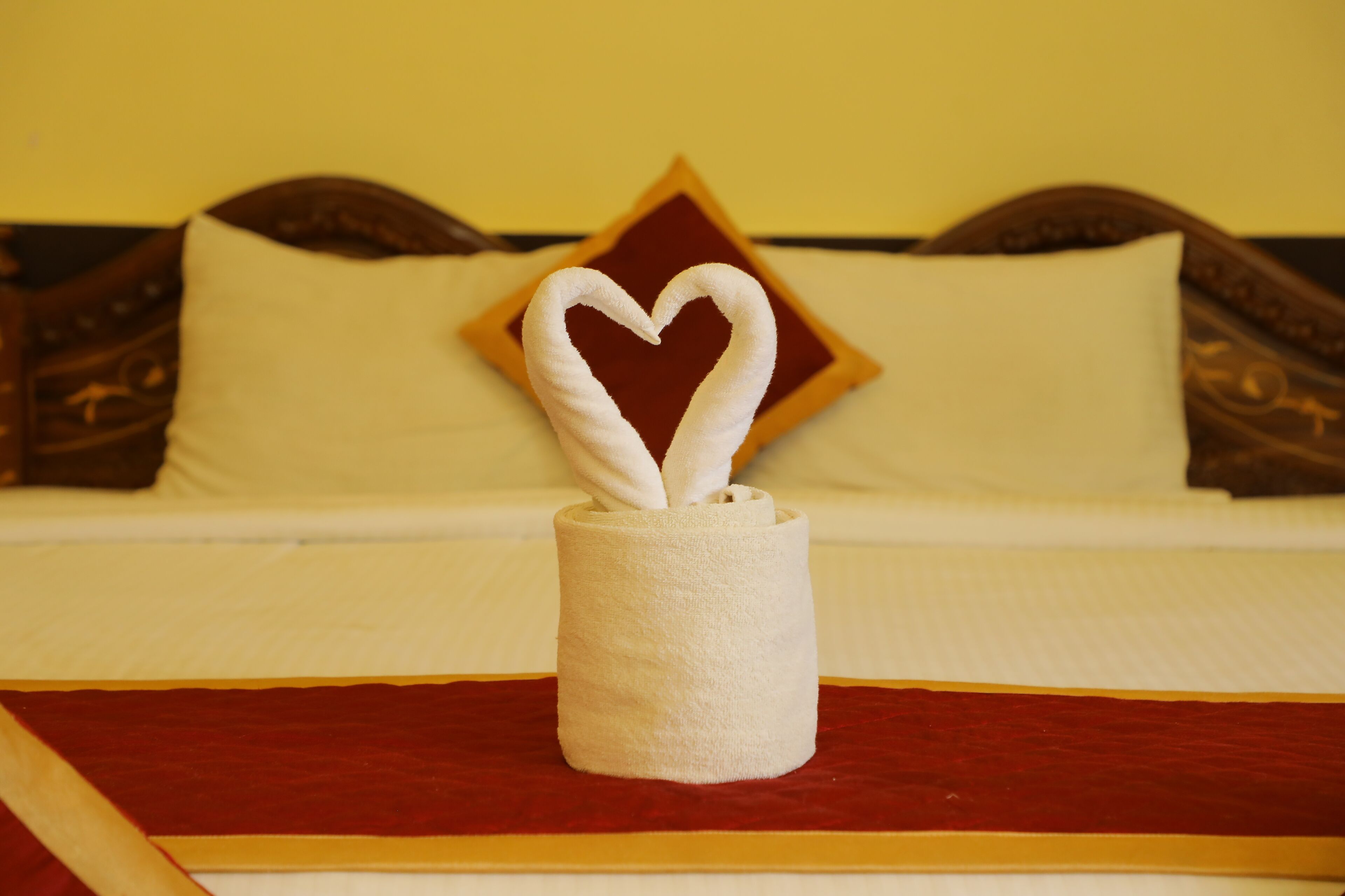 Una cama bien hecha con una toalla en forma de corazón en el centro.