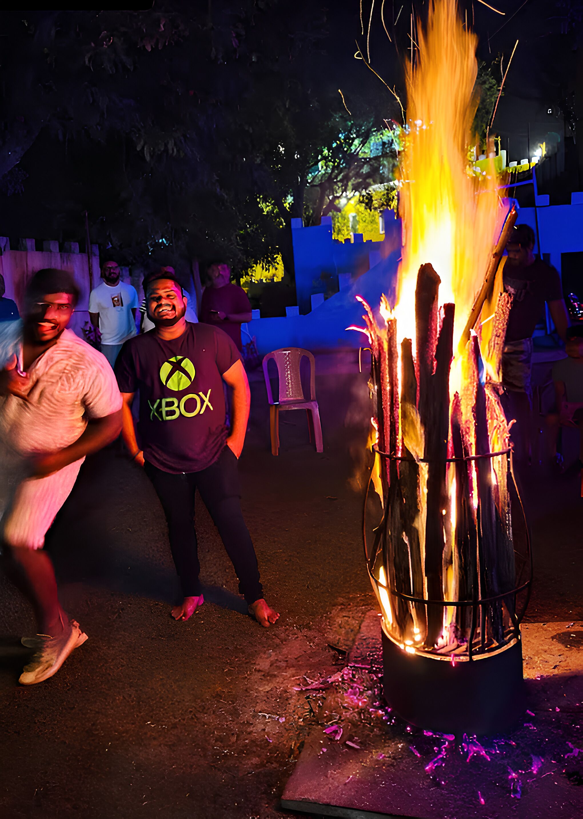 A group of people gathered around a fire pit with burning sticks.