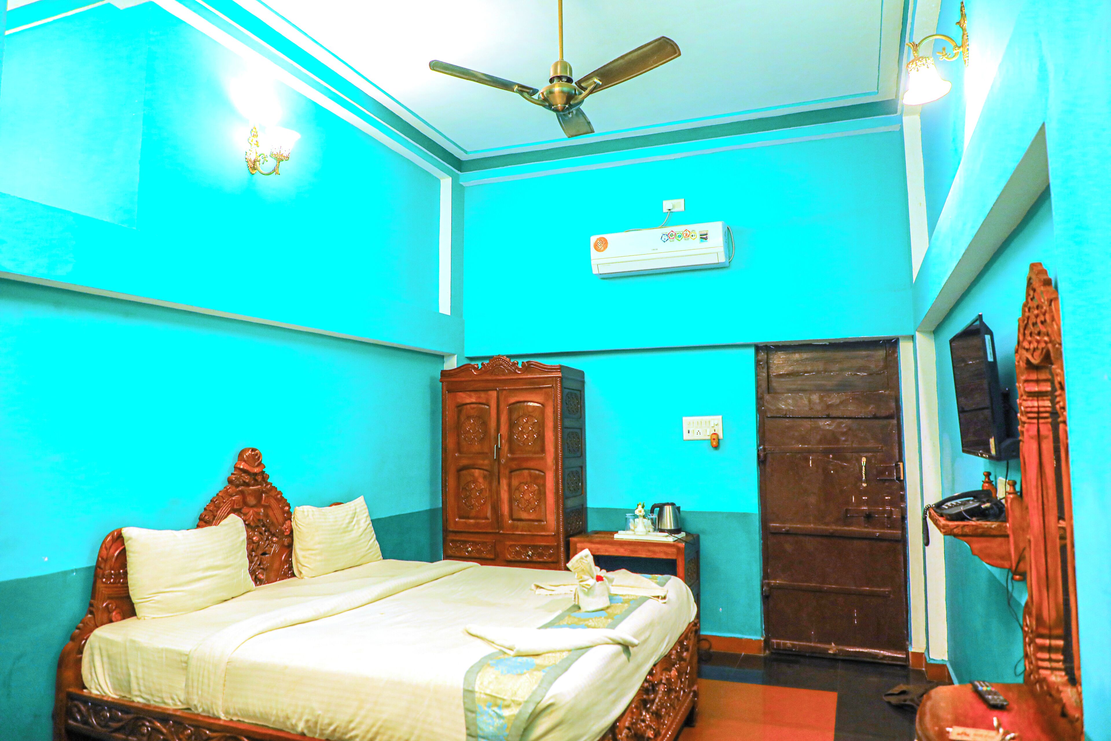 A room with a bed, wardrobe, ceiling fan, air conditioning unit, and a door.