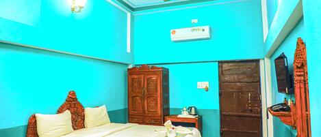 A room with a bed, wardrobe, ceiling fan, air conditioning unit, and a door.