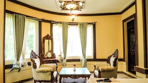 Una habitación con un ventanal grande, una araña y dos sillones decorados.