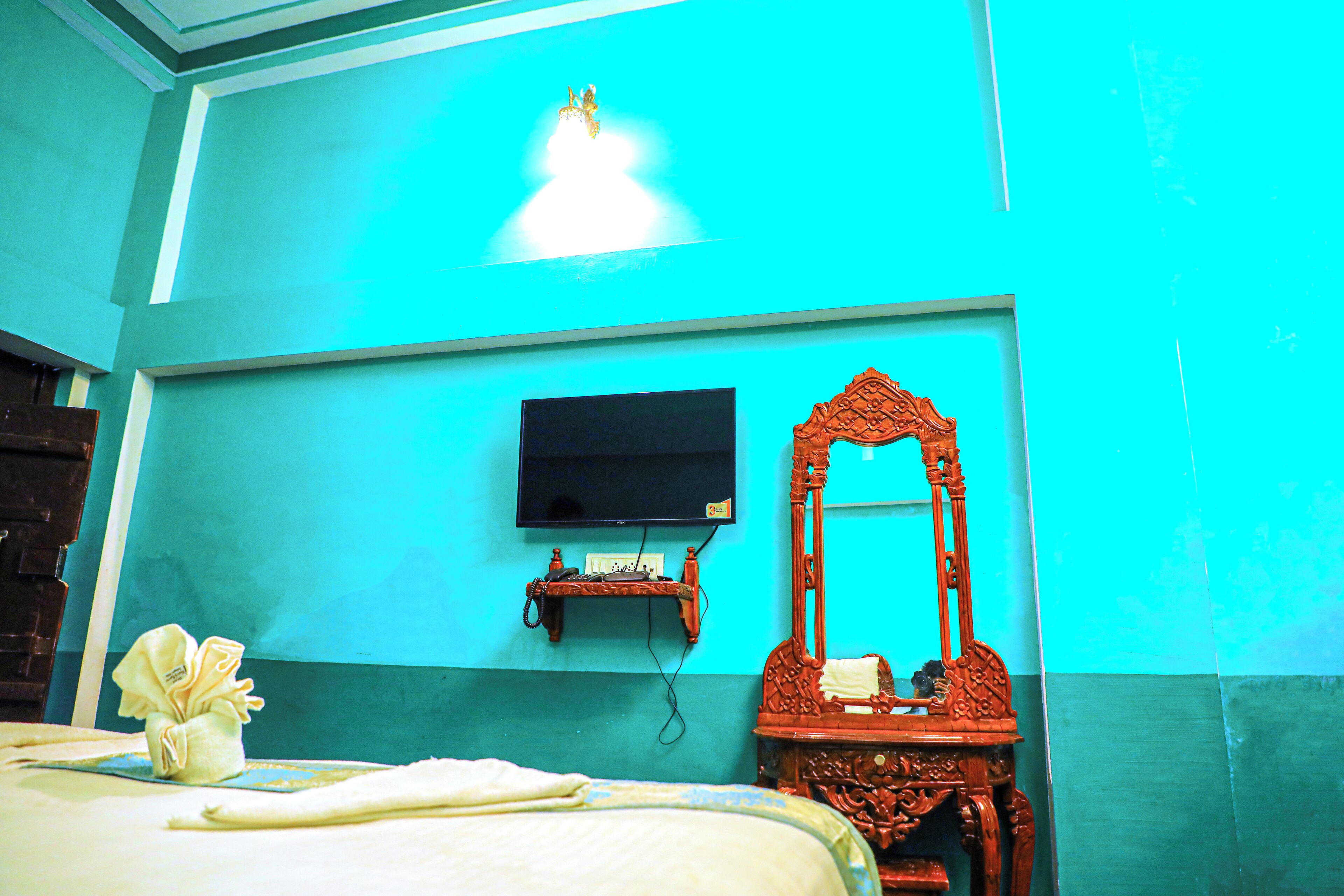 A room with a bed, a television mounted on the wall, and a wooden chair.