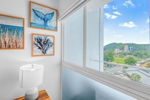 Enjoy city views from the room's large window, featuring a collection of framed artworks and a stylish side table.