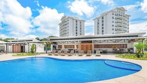 Un hôtel moderne doté d’une piscine, d’un espace extérieur aménagé et d’une zone couverte avec des parasols.