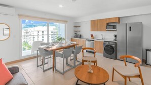 Un appartement moderne comprenant un coin repas, une cuisine et une grande fenêtre donnant sur la ville.