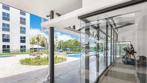 Eine moderne Hotellobby mit Glaswand, die einen Blick auf einen Außenpool und einen Parkplatz bietet.