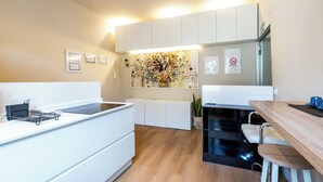 Une cuisine moderne avec des meubles blancs, un plan de travail noir et un coin repas en bois équipé de tabourets de bar.